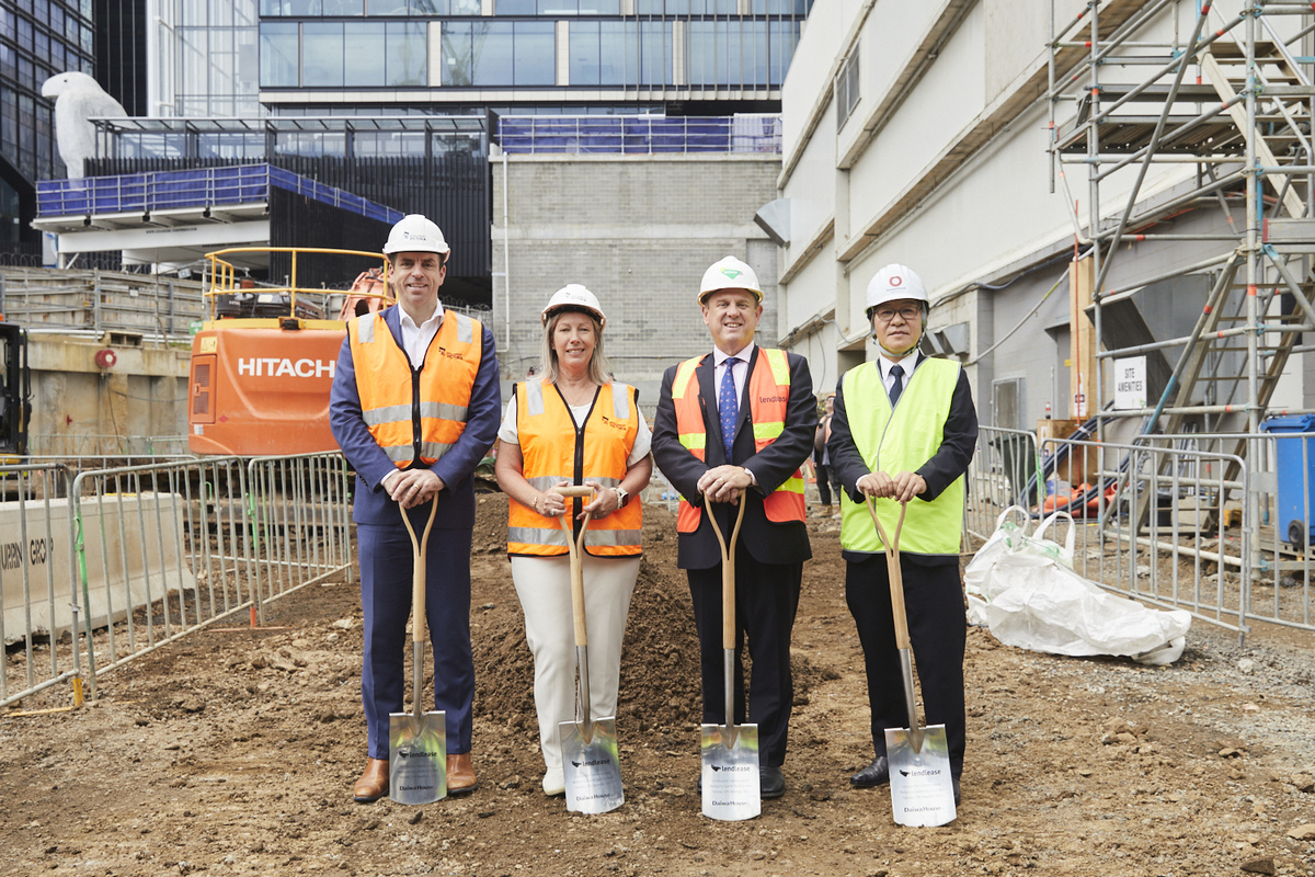 Staff in High Vic pose for aphoto with shovels, standing on a mound of soil.