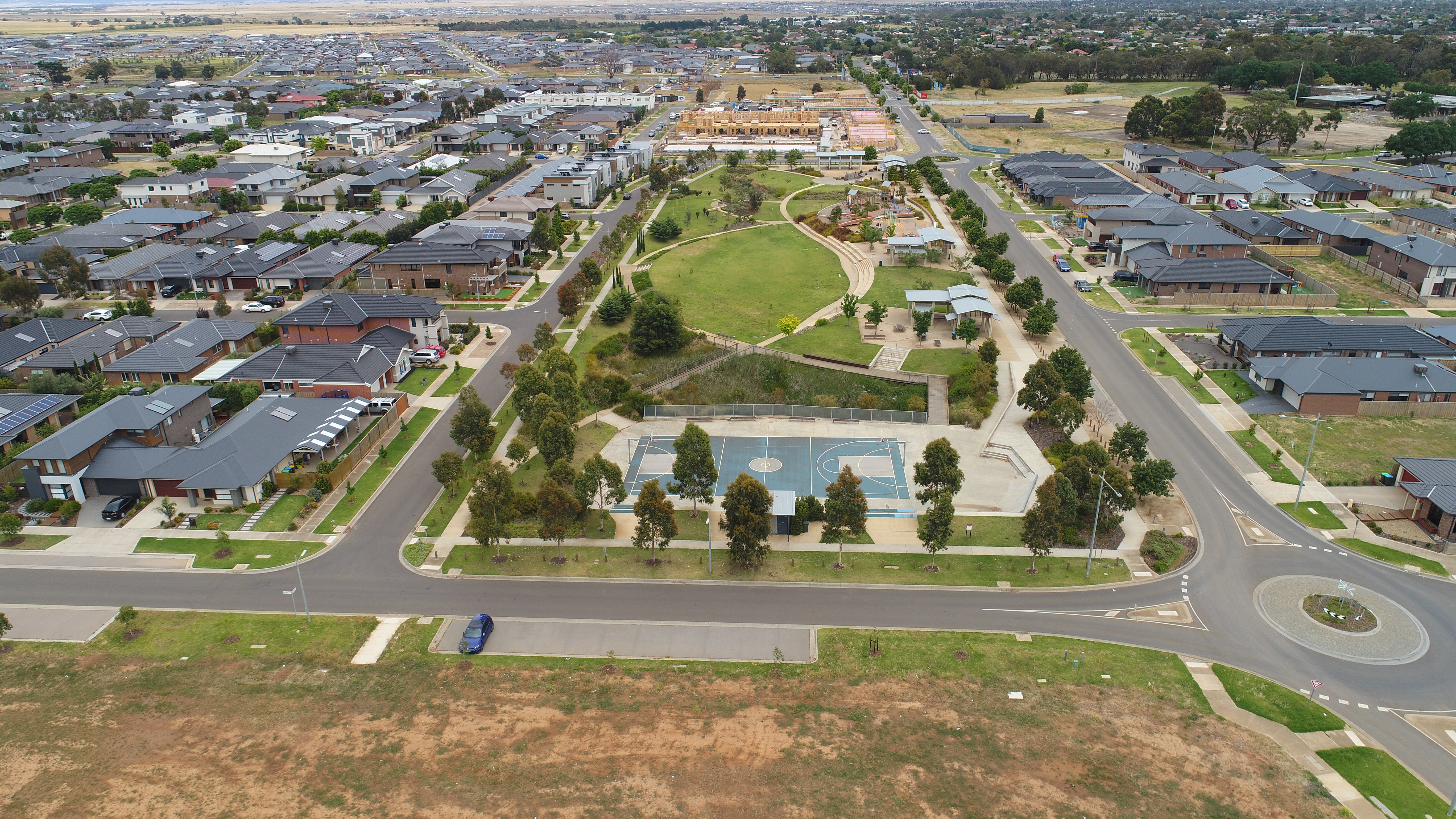 An aerial view of a park with basketball courts and houses around at Riverwalk Werribee